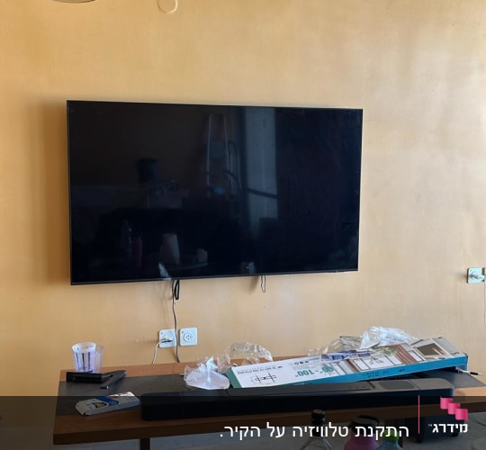 טלוויזיה מותקנת על קיר עם שולחן וכלים שונים